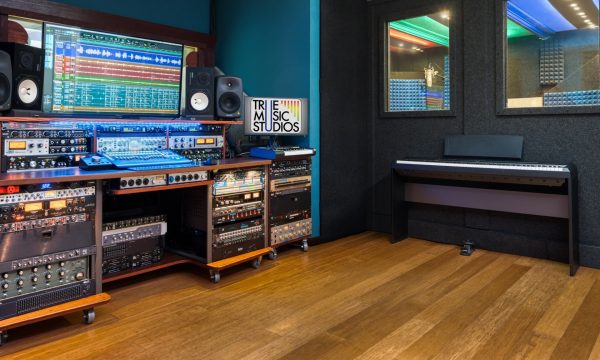 Control room desk with dual monitors showing wave graphics and True Music Studios logo, racks of Avalon and Universal Audio gear below.