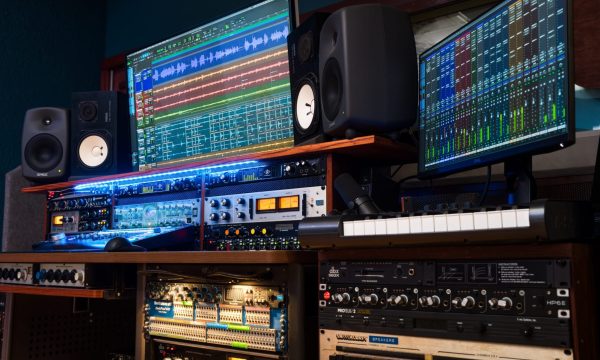 Upward left-angle view of dual displays with wave graphics, Avalon preamp in rack below.