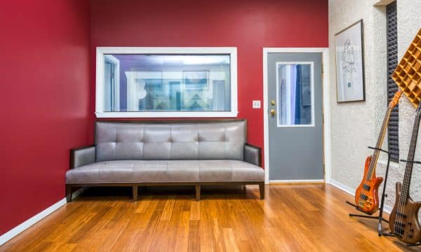 Live room with bold red wall and couch seating next to instruments.