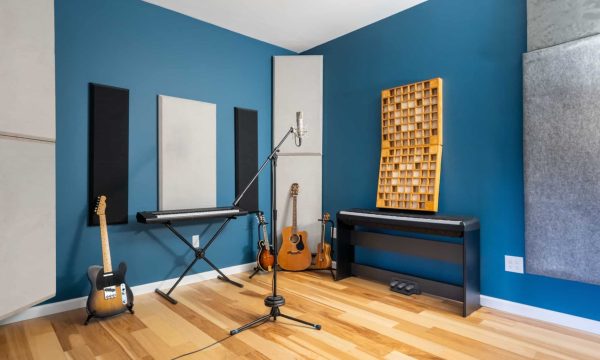 Room C corner with upright piano and microphone stand near wood acoustic panels.
